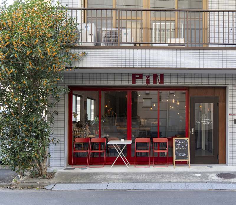 1階がカフェ PiN の建物の外観。赤い入口と PiN の看板が目印。alca は同じ建物の2階