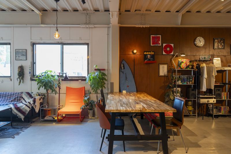 大きな木のテーブルがある、同じ建物の1階のカフェ PiN の店内